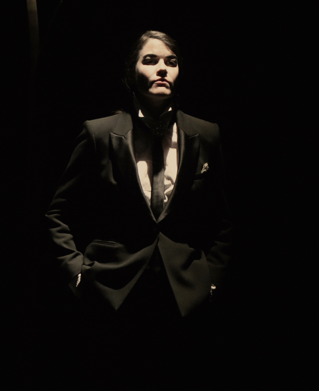 Fig. 3. Angélique portant un costume noir, une cravate noire, une chemise blanche et des chaussures à talonnettes (La Folle Enchère, théâtre de l’Épée de Bois, Paris, 2021).